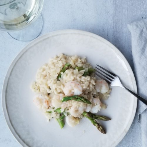 Shrimp and asparagus risotto on a white plate with a fork